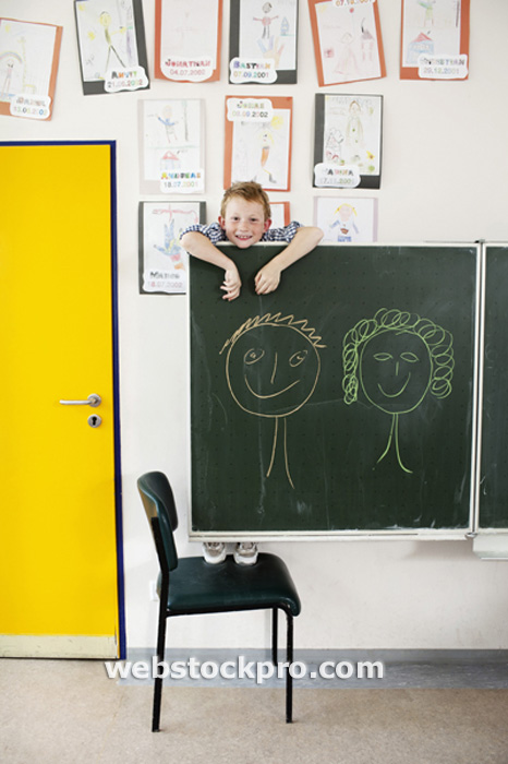 Boy hanging on blackboard stock photo