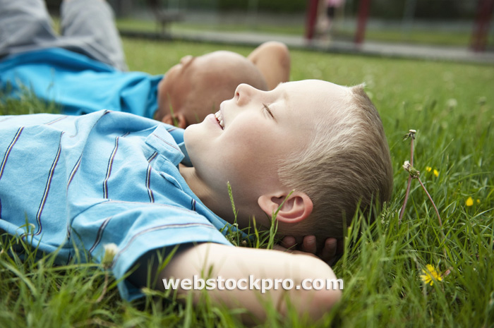 Boys resting laying in grass Stock Photo