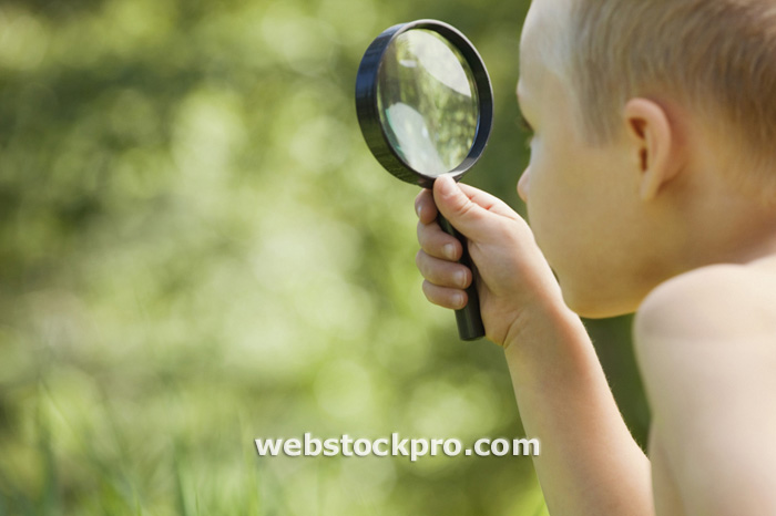 Little boy with a magnifying glass stock photo