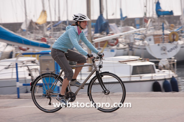 Italy, Trento, Mid adult woman cycling by harbour in Riva