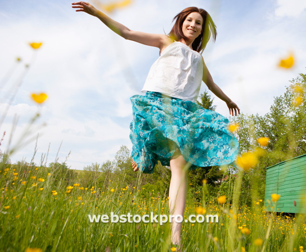 Austria, Young woman running in field of flowers