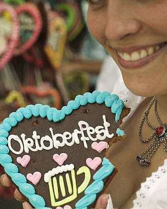 Woman holding Lebkuchen heart, a bite taken, at Oktoberfest Stock Photo