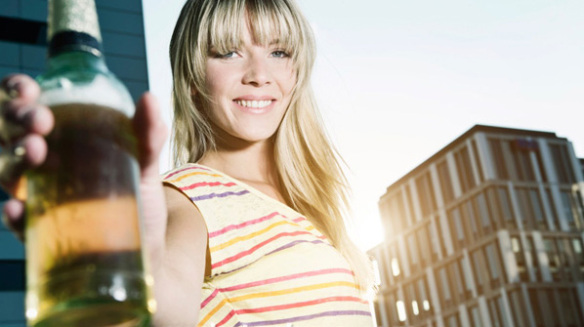 Young woman holding beer bottle, smiling, portrait Stock Photo