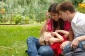 Parents together with little girl have rest in summer garden Girl plays in lap parents Photo (3929435)