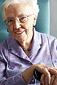 Senior Woman Relaxing In Chair Holding Walking Stick Photo (MON288051)